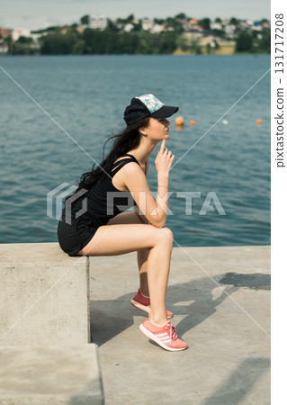 An athlete with a toned figure is sitting by the clear water An athlete with a toned figure is sitting by the clear water 131717208