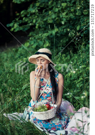 A girl at a picnic wearing a hat and a floral dress 131717219