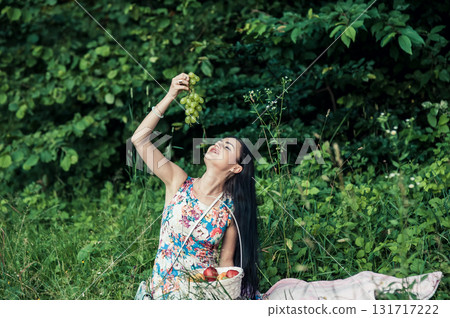 A young girl is sitting on a pink rug and holding a bunch of green grapes in her hands A young girl is sitting on a pink rug and holding a bunch of green grapes in her hands 131717222