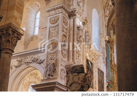 Interior of an old cathedral with intricate stone carvings and columns. Religious architecture with historical reliefs and statues Interior of an old cathedral with intricate stone carvings and columns. Religious architecture with historical reliefs and statues 131717479