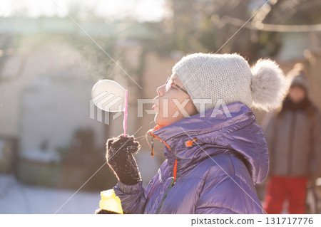 Child blowing bubbles in frosty sunshine 131717776