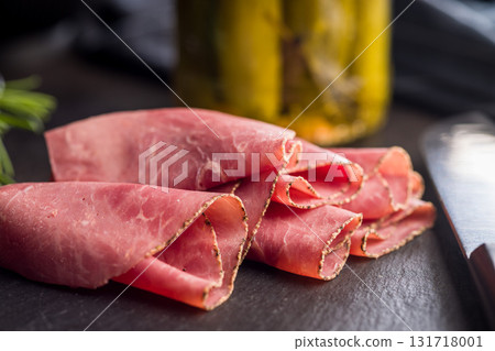 Sliced beef pastrami on black table. 131718001