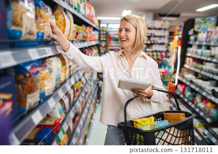 Woman shopping for groceries at supermarket aisle 131718011