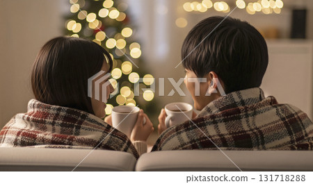 Couples snuggle under a blanket in front of a fireplace, drinking hot cocoa Couples snuggle under a blanket in front of a fireplace, drinking hot cocoa 131718288