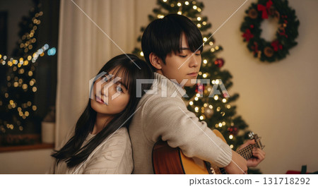 Lovers cuddling in a warmly lit room playing guitar 131718292