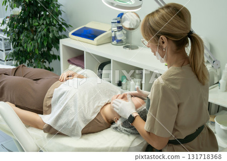 Cosmetology Treatment Facial Skincare Clinic: Professional performs facial treatment on client. Cosmetology Treatment Facial Skincare Clinic: Professional performs facial treatment on client. 131718368