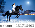 A woman in a white dress jumping on horseback on a snowy moonlit night 131718403