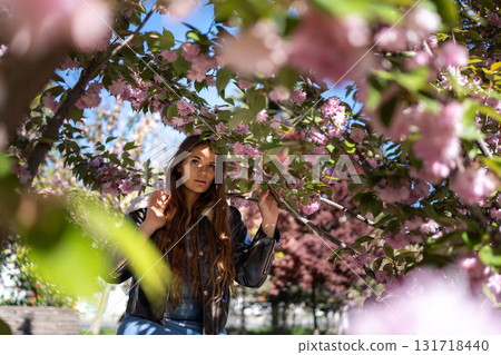 Cherryblossom Woman Jacket: Attractive female poses near blossom trees during daytime in spring, relaxation. 131718440
