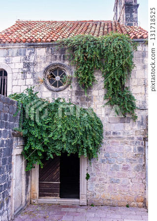 Old Stone Building Facade with Arched Wooden Door and Lush Green Vine, Budva Old Town Old Stone Building Facade with Arched Wooden Door and Lush Green Vine, Budva Old Town 131718525