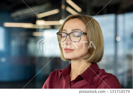 Businesswoman wearing glasses practices mindfulness, finding peace and tranquility amidst the bustling office environment, promoting mental well-being and stress reduction in the workplace Businesswoman wearing glasses practices mindfulness, finding peace and tranquility amidst the bustling office environment, promoting mental well-being and stress reduction in the workplace 131718579