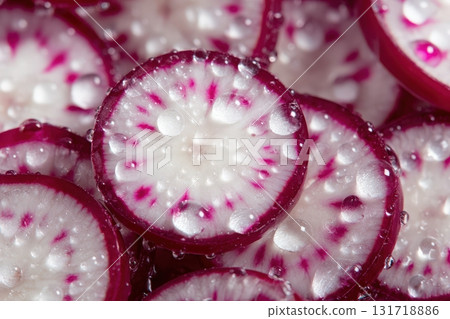 Close-up view of freshly sliced radishes showing vibrant red and white patterns. Water droplets cling to the surfaces, enhancing the freshness and appeal of the vegetable pieces. 131718886