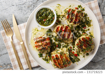 Grilled chimichurri chicken thighs with garlic, herbs and vegetable oil close-up in a plate. Horizontal top view Grilled chimichurri chicken thighs with garlic, herbs and vegetable oil close-up in a plate. Horizontal top view 131719223