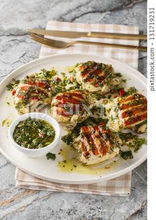 Grilled chicken thighs with Argentinian chimichurri sauce closeup on the plate. Vertical 131719231