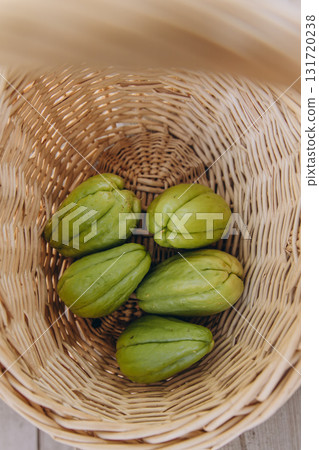 Several fresh green chayote fruits in a wicker basket top view. Organic tropical vegetable harvest. Healthy vegan food and sustainable farming concept Several fresh green chayote fruits in a wicker basket top view. Organic tropical vegetable harvest. Healthy vegan food and sustainable farming concept 131720238