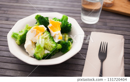 boiled broccoli inflorescences with boiled egg in plate 131720404