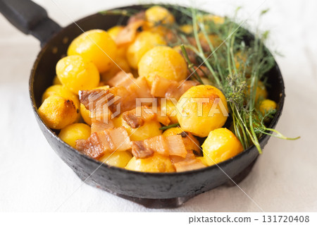 Delicious freshly cooked fried new potatoes with bacon, served in a frying pan Delicious freshly cooked fried new potatoes with bacon, served in a frying pan 131720408
