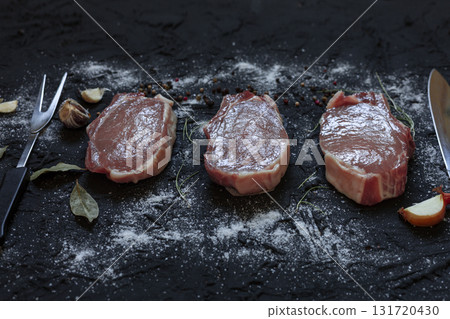 Raw pork chops with spices, herbs and ingredients on dark rustic background, top view Raw pork chops with spices, herbs and ingredients on dark rustic background, top view 131720430