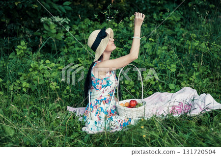 A young girl at a picnic in the park holds a large bunch of grapes against a backdrop of green trees A young girl at a picnic in the park holds a large bunch of grapes against a backdrop of green trees 131720504