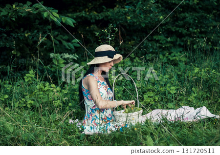 A beautiful woman relaxes at a picnic in the forest with grapes in her hands A beautiful woman relaxes at a picnic in the forest with grapes in her hands 131720511