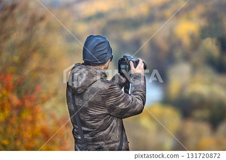 rear view of Young photographer takes pictures of autumn landscape, closeup 131720872