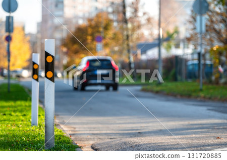 poles at the traffic safety speed bumps in a residential area, defocused background with a car poles at the traffic safety speed bumps in a residential area, defocused background with a car 131720885