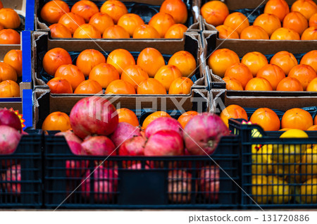rows of ripe persimmons, pomegranates and lemons in wooden boxes on the market 131720886