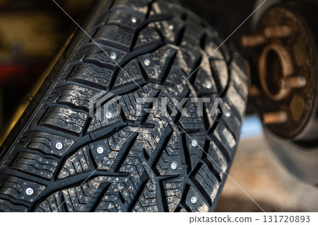 winter studded tires in the service near the car, seasonal tire change, close-up winter studded tires in the service near the car, seasonal tire change, close-up 131720893
