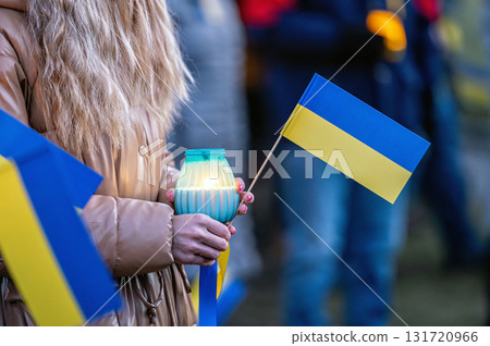 Ukrainian flags, candles and torches in the hands of protesters at the rally "Stand With Ukraine", closeup Ukrainian flags, candles and torches in the hands of protesters at the rally "Stand With Ukraine", closeup 131720966
