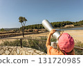 Child on safari looks through a telescope to observe wild animals in natural habitat. Wildlife watching experience for kids in nature reserve on a sunny day 131720985