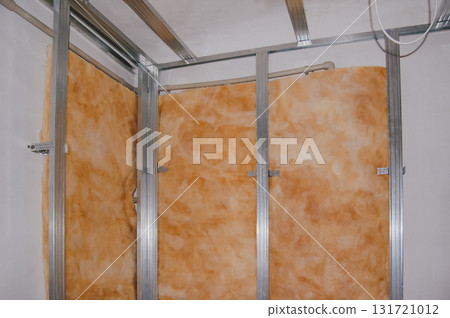 Wall insulation in old apartment with metal frame and orange mineral wool for soundproofing. 131721012