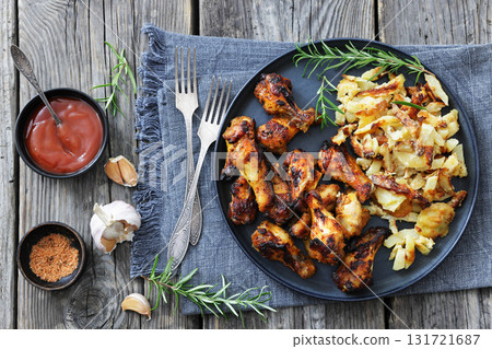 bbq chicken wings with fried potatoes on plate 131721687