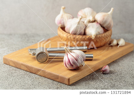 Garlic and garlic press on a wooden cutting board. Garlic and garlic press on a wooden cutting board. 131721894