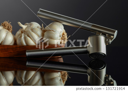 Garlic bulbs and garlic press on a black background. Garlic bulbs and garlic press on a black background. 131721914