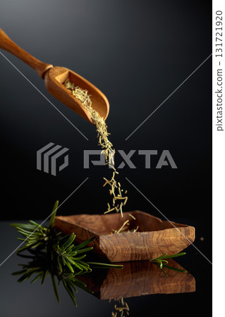 Dry rosemary are poured into a wooden bowl. Dry rosemary are poured into a wooden bowl. 131721920