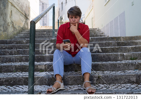 Sad woman sitting on stairs with a phone. no signal, no money, or afraid to call her boyfriend 131722013