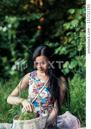 A lady in a light floral dress sits on a pink rug surrounded by nature 131722150