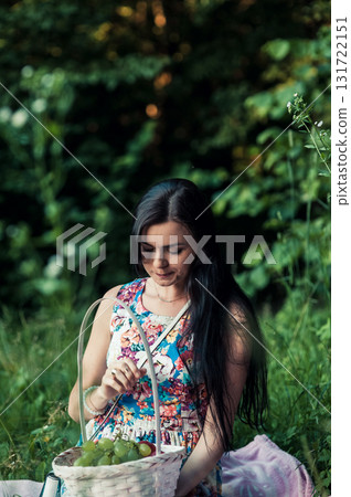 A lady in a light floral dress sits on a pink rug surrounded by nature 131722151