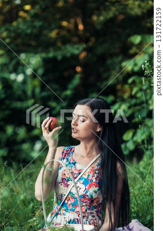 A lady in a light floral dress sits on a pink rug surrounded by nature 131722159