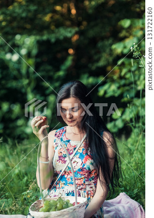 A lady in a light floral dress sits on a pink rug surrounded by nature 131722160