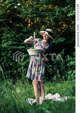 A seductive girl stands on the grass next to a pink picnic blanket A seductive girl stands on the grass next to a pink picnic blanket 131722196
