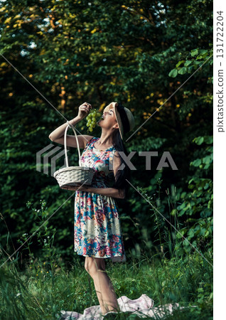 A woman in a floral dress stands next to a picnic rug A woman in a floral dress stands next to a picnic rug 131722204