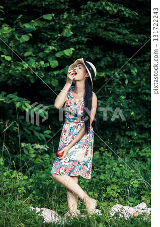 A young girl stands in the green forest with two red apples A young girl stands in the green forest with two red apples 131722243