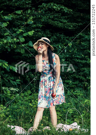 A woman in a floral dress holds two red apples A woman in a floral dress holds two red apples 131722245