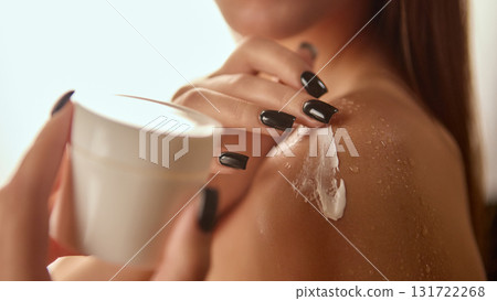 Woman applying body cream on shoulder with elegant manicure and water drops 131722268