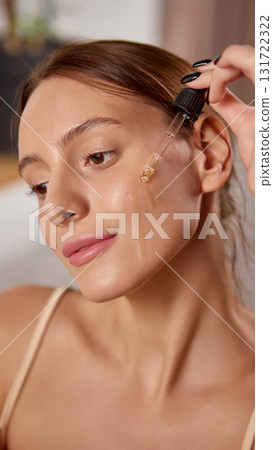 Woman applying face serum with dropper for skincare hydration and radiance 131722322