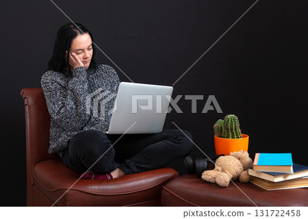 focused young freelance woman sitting with laptop and headphones, working remotely online from home 131722458