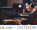 smiling asian male music producer, musician, guitarist, artist playing and recording electric guitar in home studio. recording concept 131722594