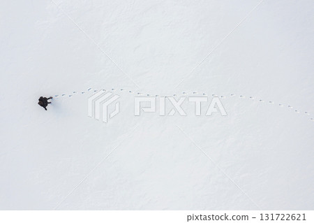 a woman walks through fresh snow leaving footprints, top aerial view, winter outdoor activity a woman walks through fresh snow leaving footprints, top aerial view, winter outdoor activity 131722621