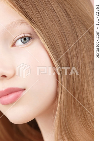 Half face portrait of a funny smiling young girl. Blonde Caucasian girl with blue eyes isolated on pink background. Ads concept skin care for teenagers. Hair care. Copy space. Self care Gen Alpha 131722861