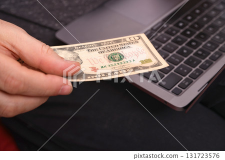 man with laptop on lap and money in hands, close-up, online business concept man with laptop on lap and money in hands, close-up, online business concept 131723576